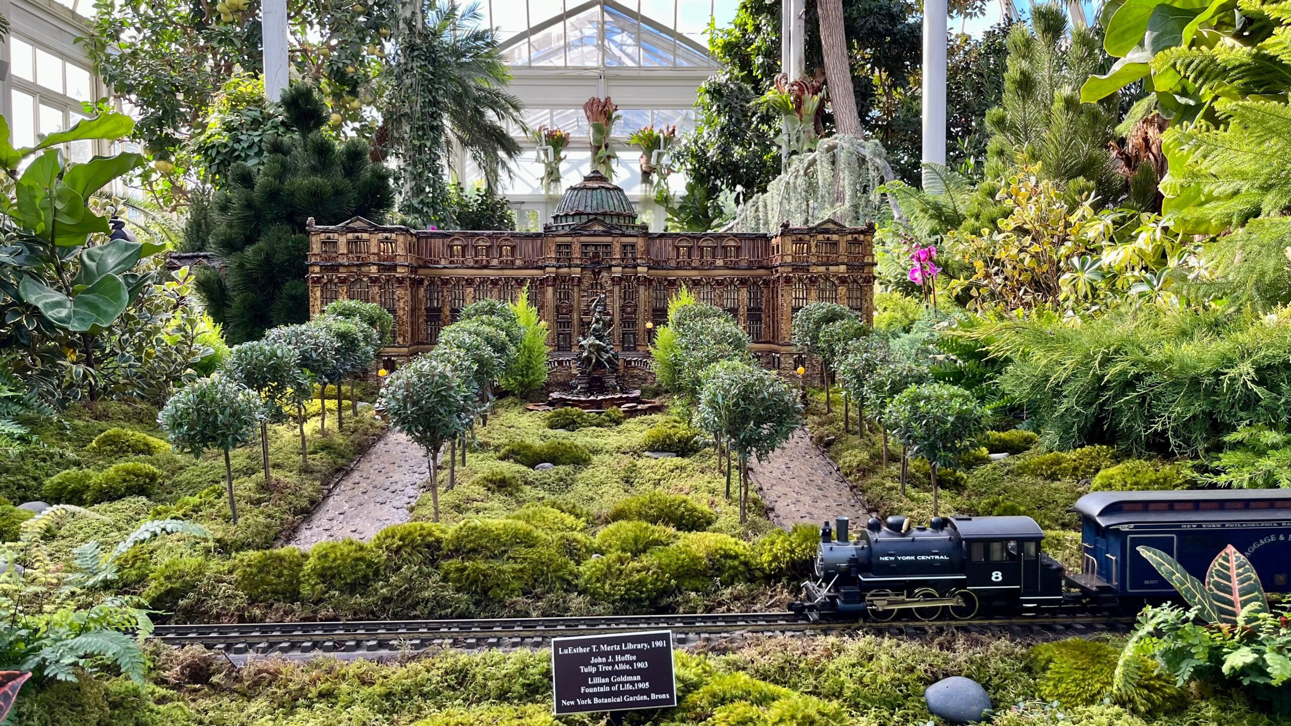 A detailed botanical model of a historical building and a miniature New York Central train on a track at the Holiday Train Show in the New York Botanical Garden, a cultural gem near the best neighborhoods in the Bronx.