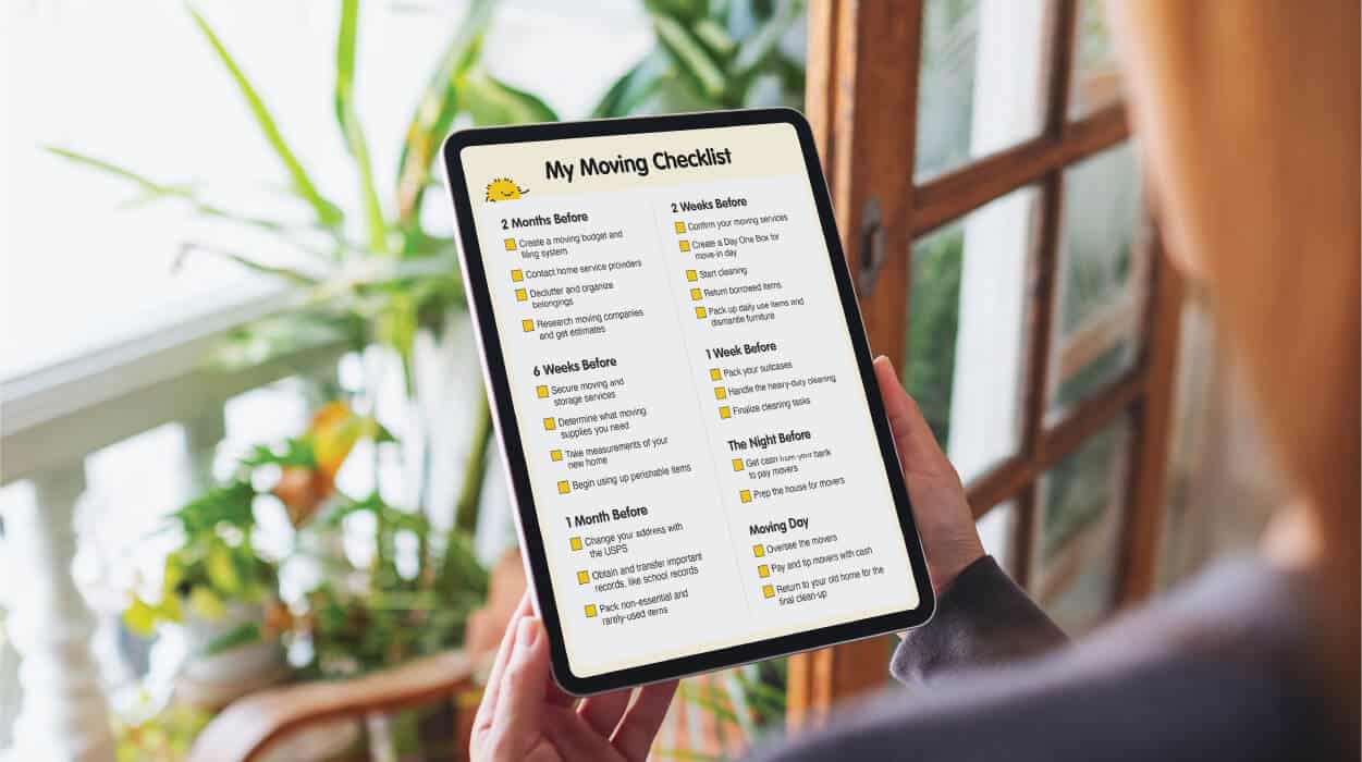 An over-the-shoulder view of a person holding a tablet device showing SpareFoot’s moving checklist on screen.