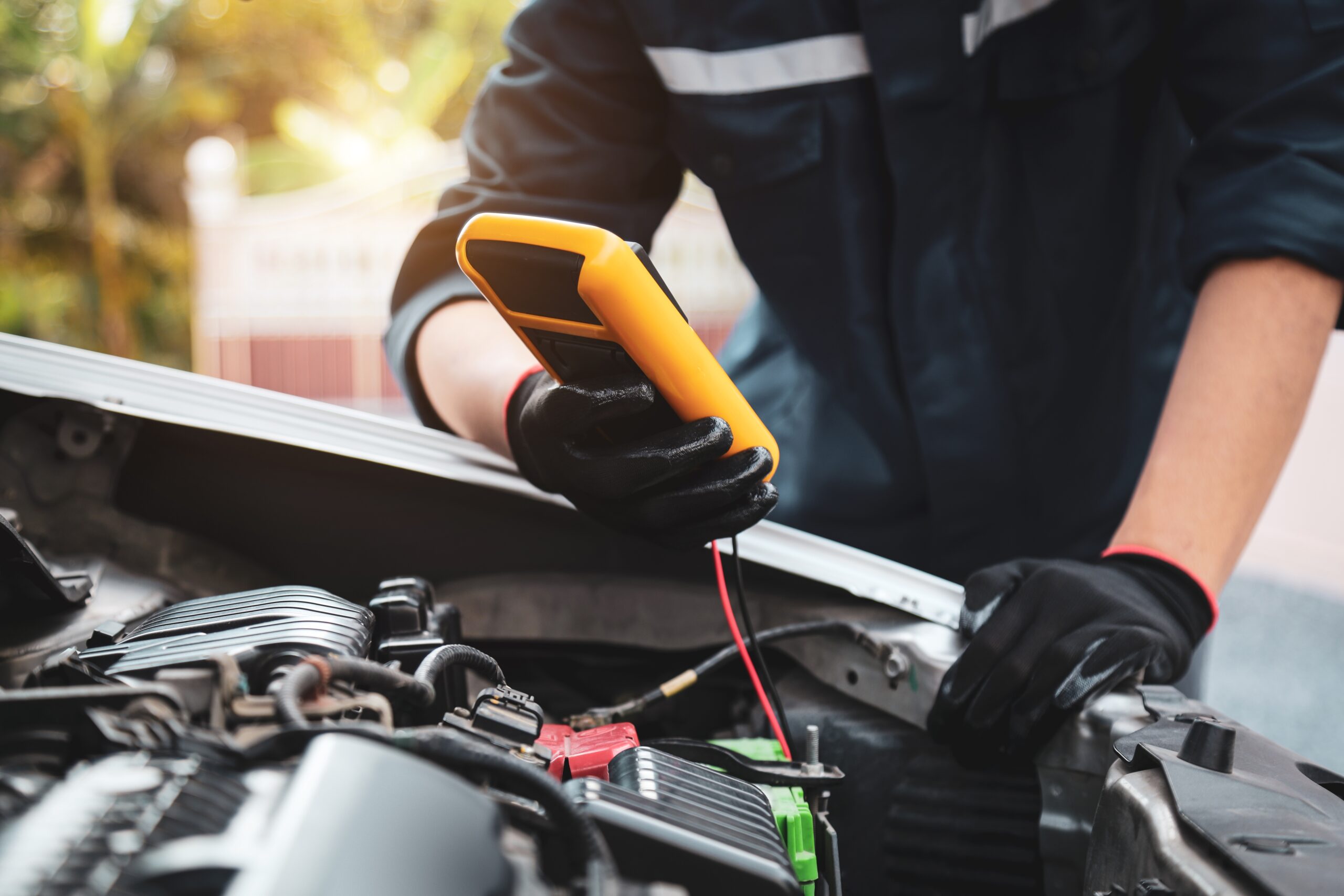A person holding a voltmeter to check a car's battery