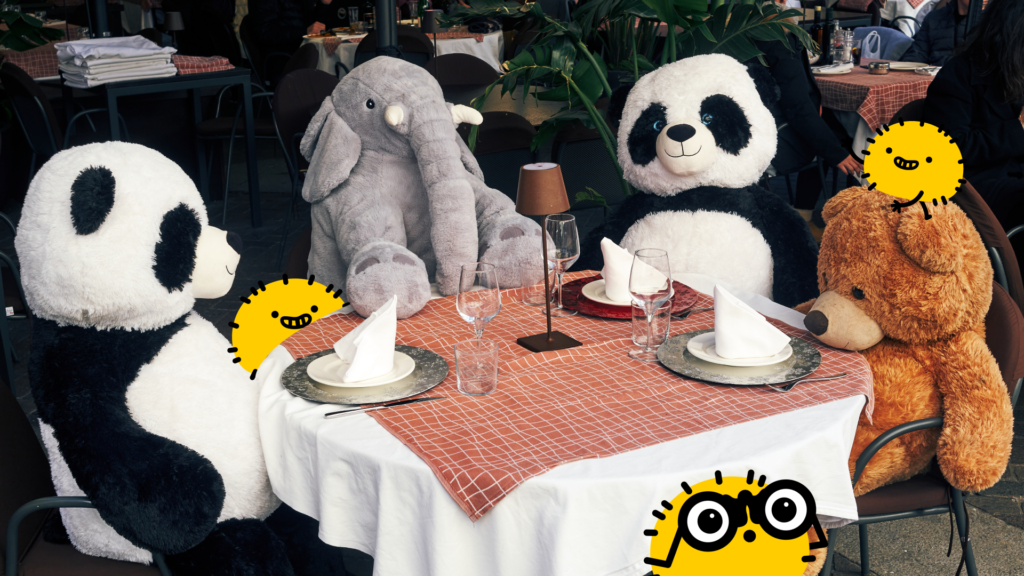 A photo features giant plush pandas, an elephant, and a teddy bear sitting at a set restaurant table alongside whimsical yellow cartoon characters. This playful dining scene acts as an eye-catching cover image for a guide on how to store stuffed animals.