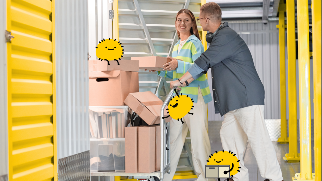 A smiling young couple unloads cardboard boxes from a moving cart into a locker with bright yellow roll-up doors, accompanied by playful yellow cartoon characters. This cheerful moving day scene serves as an inviting cover graphic for a guide on maximizing a standard non-climate controlled storage unit.