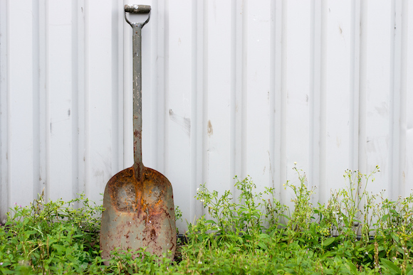 rusty shovel leaning on shed