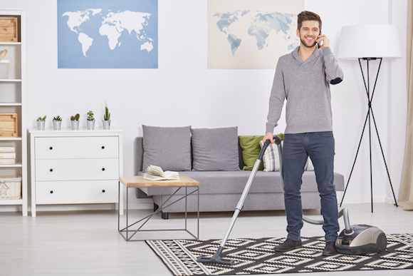 Happy man vacuuming