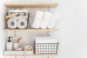 Nice white bathroom. Wooden shelves. Towels, stacked towels and baskets.