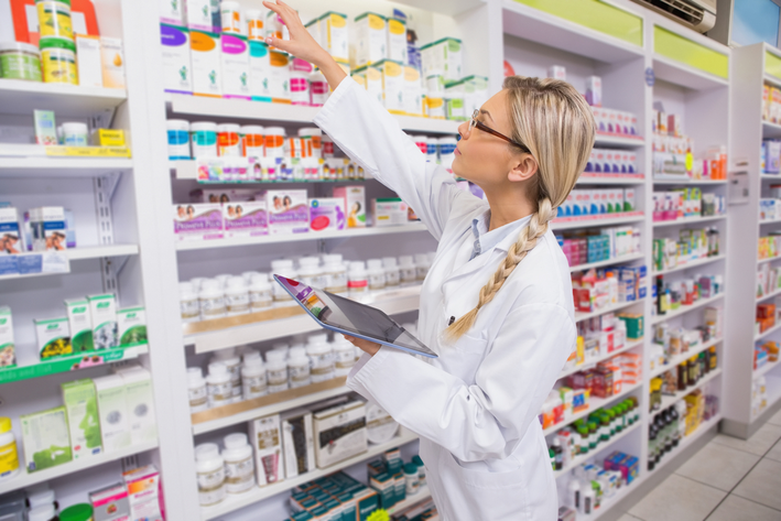 pharmacist taking medicine from shelf in pharmacy